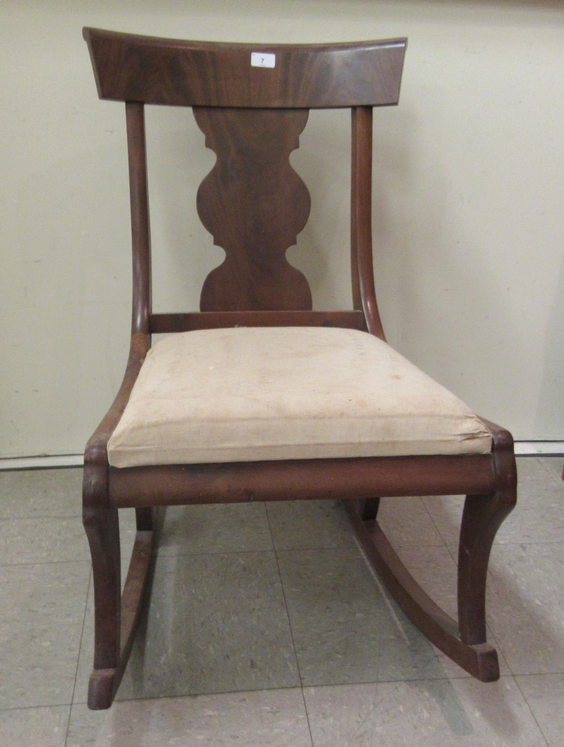 A 19thC and later mahogany framed rocking chair with a curved bar crest and vase design splat, the