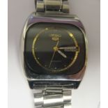 A vintage Seiko 5 automatic, stainless steel cased bracelet wristwatch, faced by a black and gilt