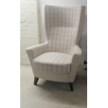 A modern high wingback, enclosed arm chair, upholstered in biscuit coloured check fabric with a