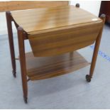 A 1950s Vanson mahogany two tier tea trolley with fall flaps, raised on turned legs and casters