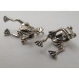 A pair of silver coloured metal earrings, fashioned as frogs