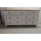 A modern cream and naturally coloured dressing chest, comprising an arrangement of nine drawers with