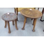 An African native carved, wooden table stool with a dished top, raised on four tapered legs and