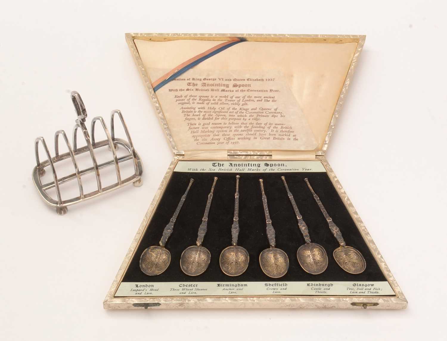 A 1930s cased set of silver spoons, and a silver toast rack.