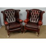 A pair of red leather wing-back armchairs.