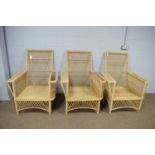 Three mid-century plantation style wicker conservatory armchairs.