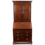 A George III mahogany and banded bureau cabinet, the upper section with cavetto cornice, above a