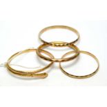 A gold snake pattern bangle and three others.