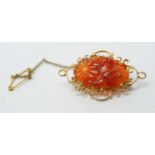 A carved carnelian and yellow metal brooch