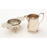 A silver jug and tea strainer on stand.