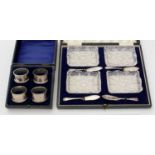 A set of four silver napkin rings, cased; together with a set of four cut glass butter dishes,