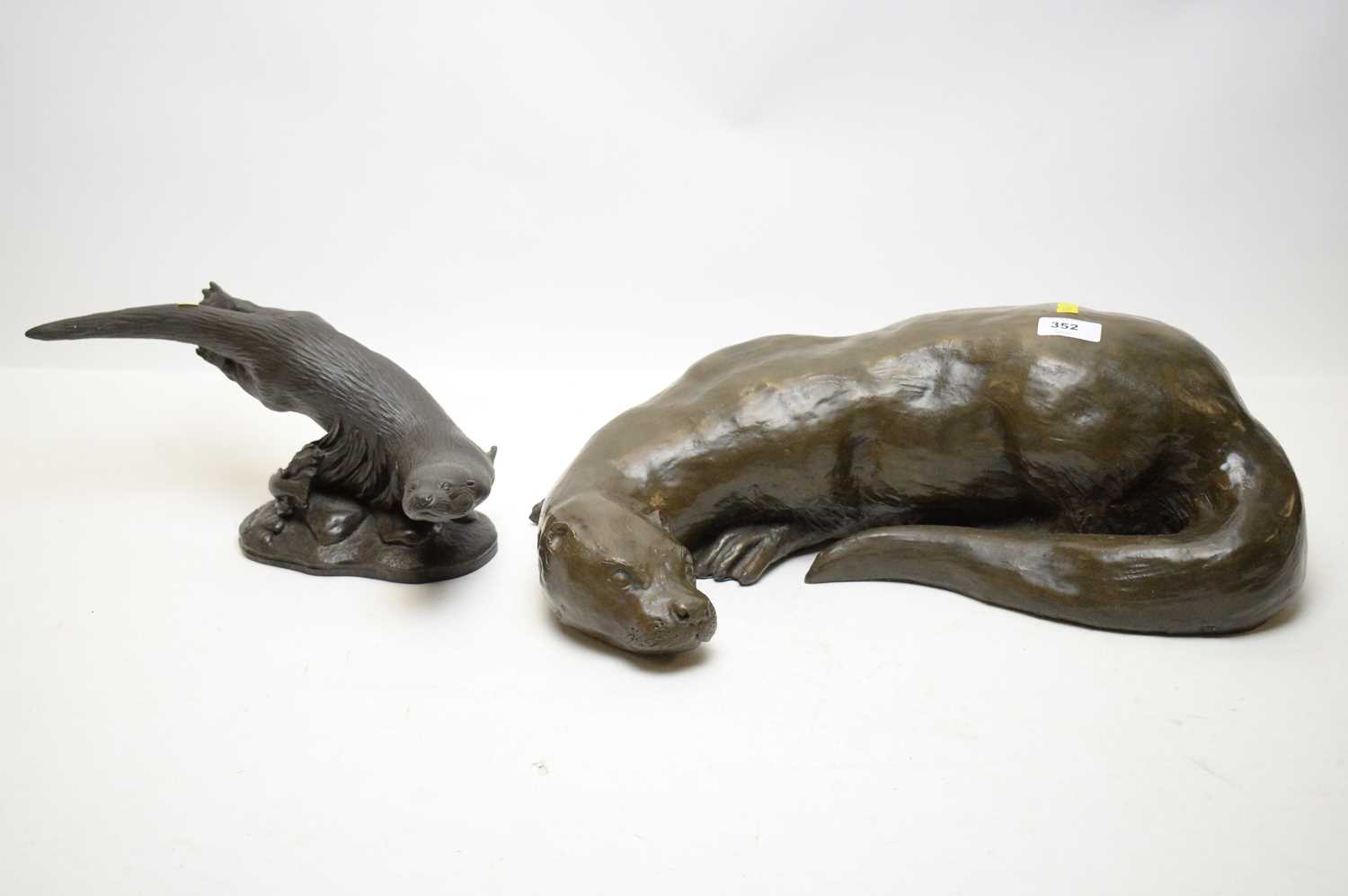 Two bronzed sculptures of otters.