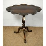 A Victorian-style carved mahogany tilt action tripod table.