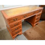 A reproduction yew-veneered nine drawer twin pedestal desk