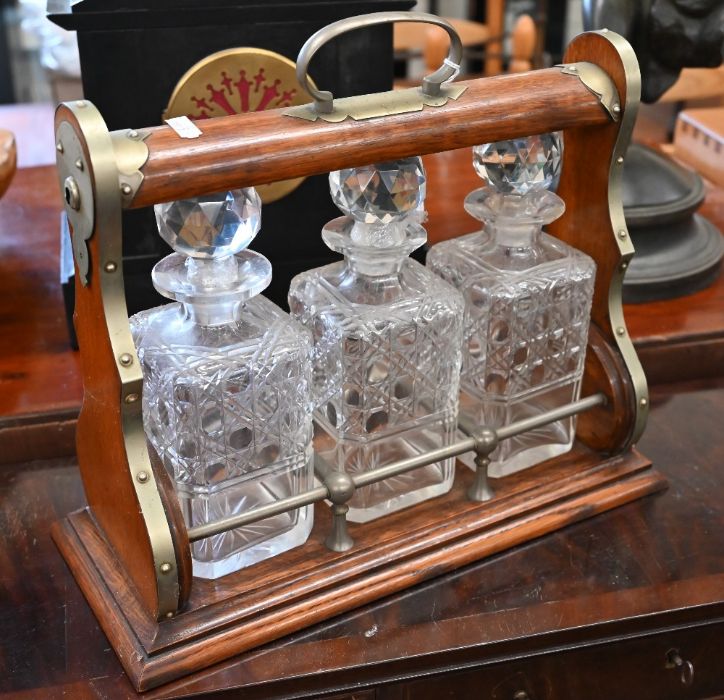 An oak tantalus with nickel mounts and three square cut glass decanters