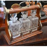 An oak tantalus with nickel mounts and three square cut glass decanters