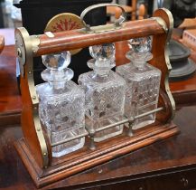 An oak tantalus with nickel mounts and three square cut glass decanters