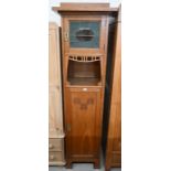 An Arts and Crafts narrow oak hall cupboard