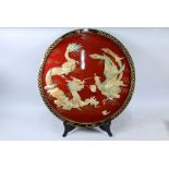 A Chinese red lacquered dragon and phoenix circular plaque