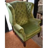 A Georgian style wing back armchair in green dralon buttoned upholstery