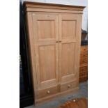 A waxed pine wardrobe with twin panelled doors