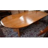 A golden oak oval dining table on twin-pedestal supports