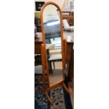 A modern arched cheval mirror in stained pine frame