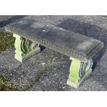 A weathered three piece cast stone garden bench