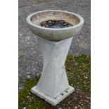 A faux marble pedestal bird bath