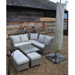 A weathered Bramblecrest rattan L-shaped sofa, table, stool and parasol