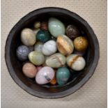 An antique copper bowl containing approx thirty onyx/hardstone eggs