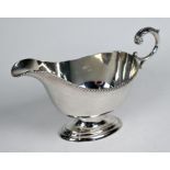 A silver saucer-boat with gadrooned rim and scroll handle