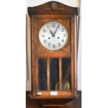 A 1930s oak cased wall clock with twin train movement