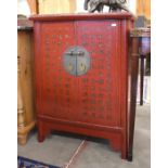 A small Chinese red lacquered two door cabinet