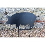 A black painted steel garden feature silhouette of a small standing pig