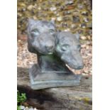 A reconstituted stone garden ornament of two greyhound heads on plinth base, aged bronzed finish