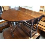 An antique oak gateleg table raised on a bobbin turned frame