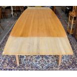 A modern stained light oak dining table with draw-leaf top