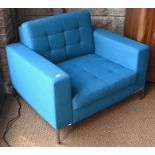 A contemporary teal blue button upholstered armchair