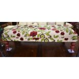 A rectangular footstool with brightly embroidered floral upholstery