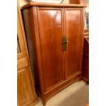 A Chinese hardwood and brass mounted two door cupboard, the interior fitted with shelves and two