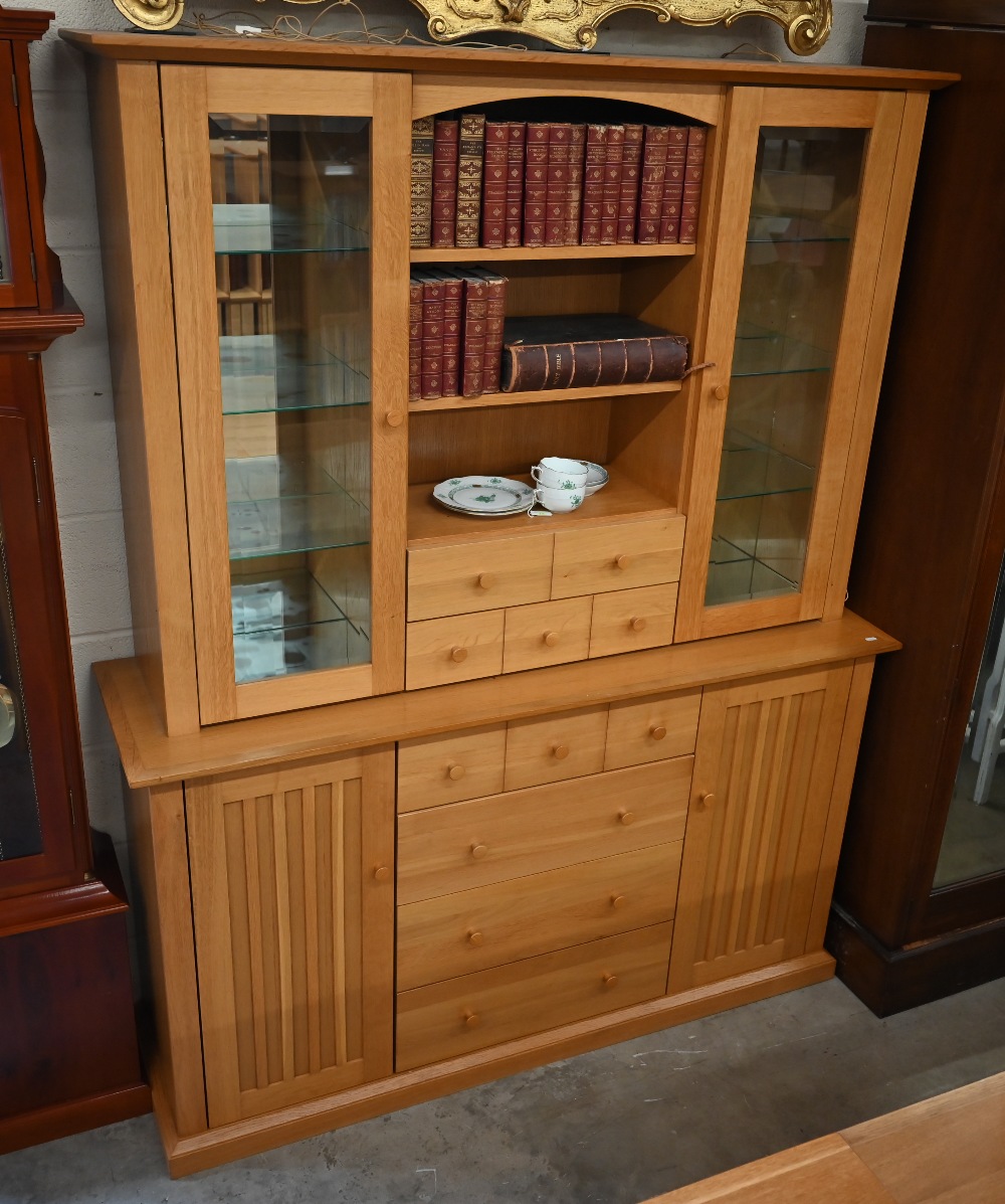 A light oak wall unit with six drawers over two cupboards, with glazed doors revealing shelves,