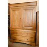 A large modern 'Chateau Collection' oak armoire with panelled doors enclosing wooden hanging rail