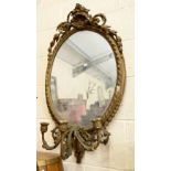 An antique oval girandole wall mirror in giltwood and gesso frame with three branch sconce