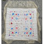 A vintage ivory silk shawl embroidered with colourful longstitch floral designs, with fringed