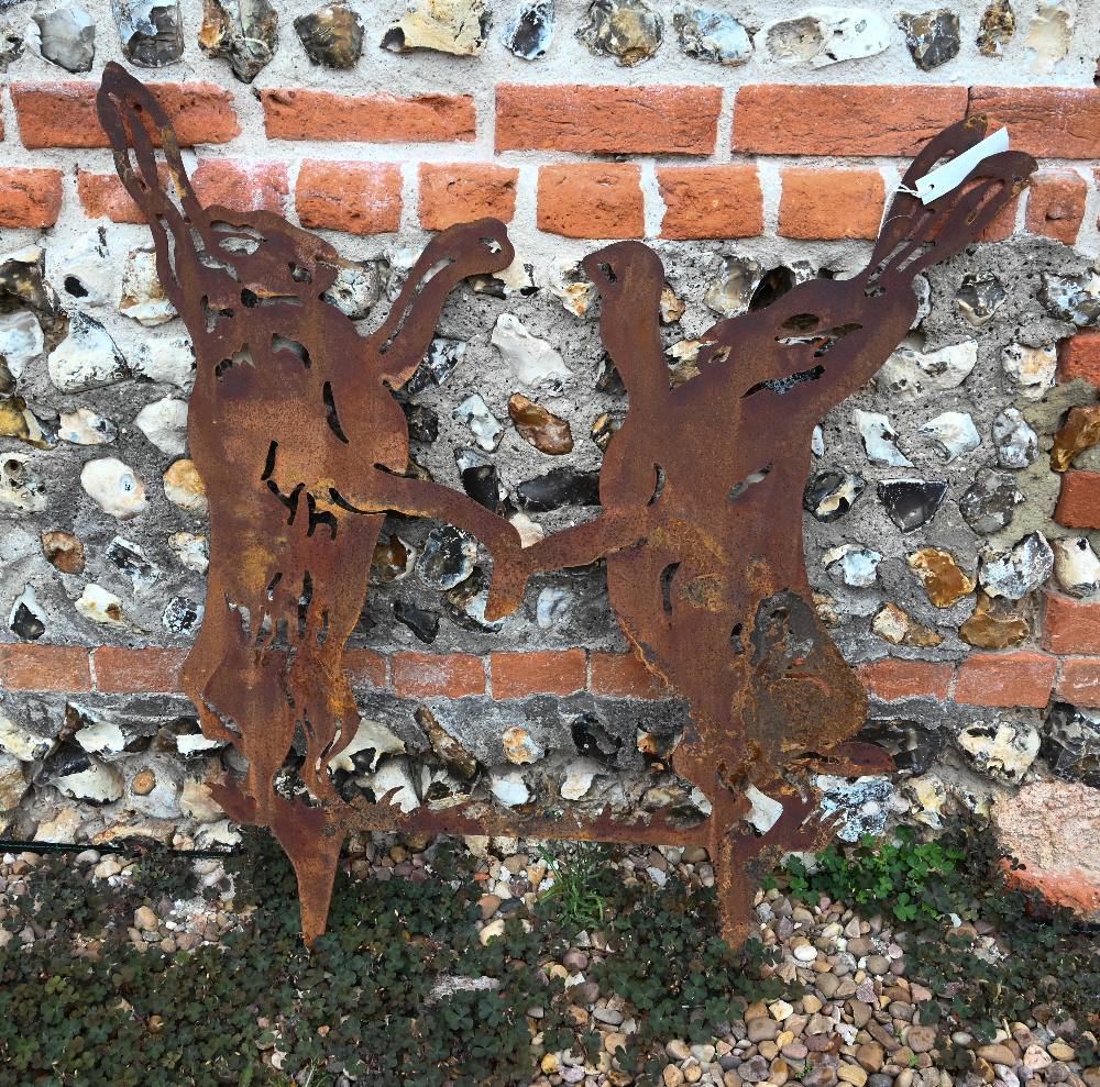 An aged steel garden feature silhouette of two boxing hares