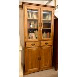 A modern oak bookcase cabinet with two drawers dividing the glazed and panelled doors, 98 cm wide