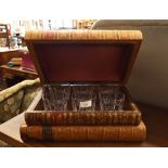 A set of six cut glass whisky tumblers concealed in a stack of leather-bound books