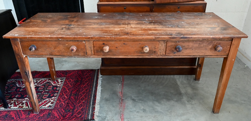 A provincial stained pine dresser base with three drawers and turned handles raised on square