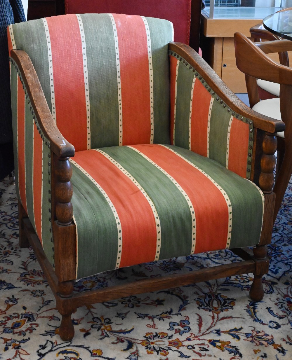 An early 20th century oak framed armchair with green and red striped fabric uphostery
